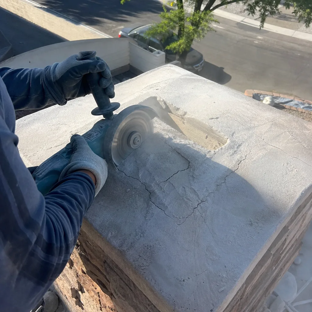Professional contractor using a masonry saw for chimney cap repair